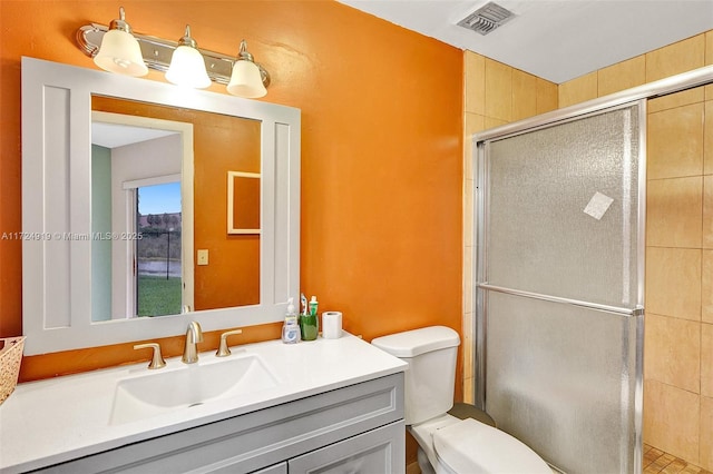 bathroom with a shower with door, vanity, and toilet