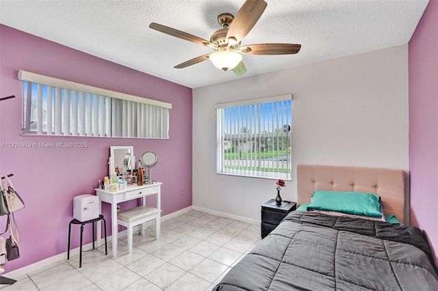 bedroom featuring ceiling fan, light tile patterned floors, and a textured ceiling