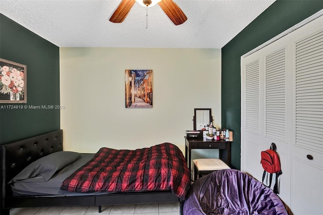 bedroom with ceiling fan, a closet, light tile patterned flooring, and a textured ceiling