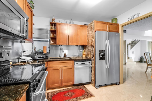 kitchen with sink, stainless steel appliances, dark stone counters, and backsplash