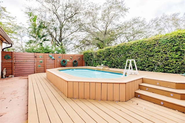 view of swimming pool featuring a deck, a fenced backyard, and a hot tub