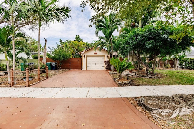 view of front of home with stucco siding, concrete driveway, a detached garage, and fence