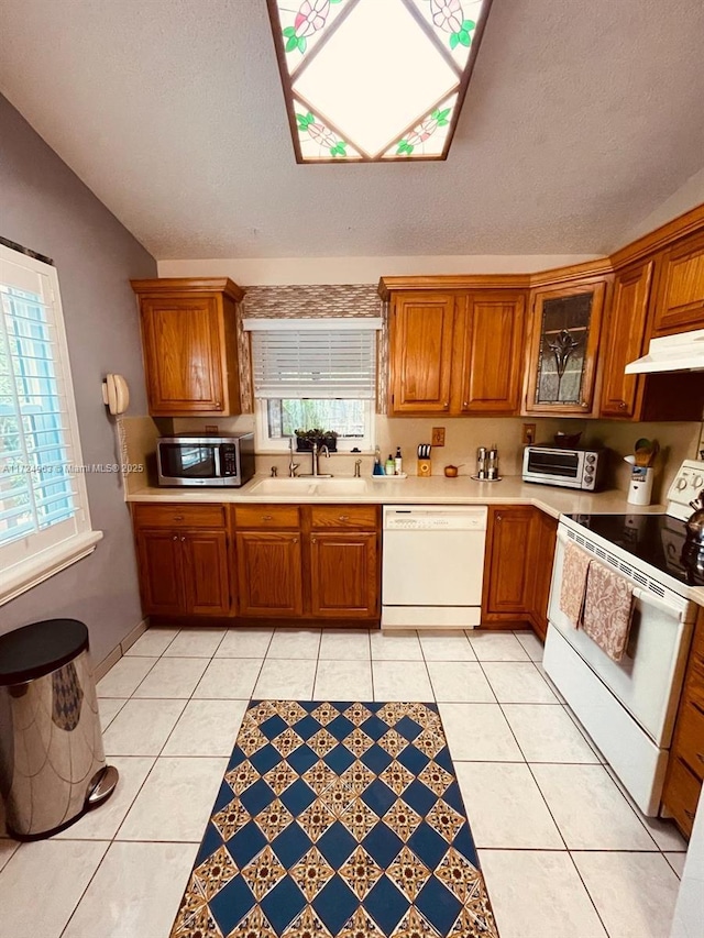 kitchen with white appliances, light tile patterned flooring, sink, and a textured ceiling