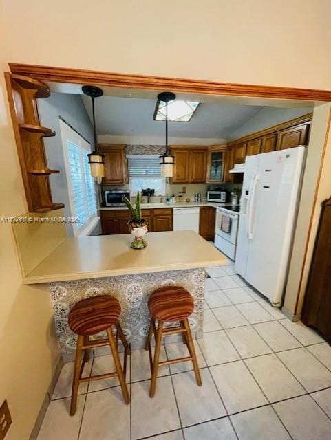 kitchen with decorative light fixtures, white appliances, kitchen peninsula, a breakfast bar area, and a healthy amount of sunlight