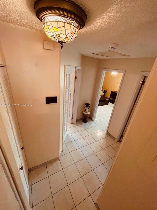 hall with light tile patterned flooring and a textured ceiling