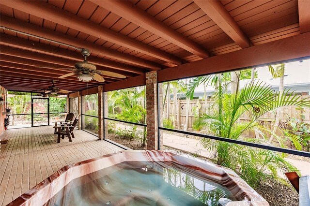 unfurnished sunroom featuring a wealth of natural light, beam ceiling, and a hot tub