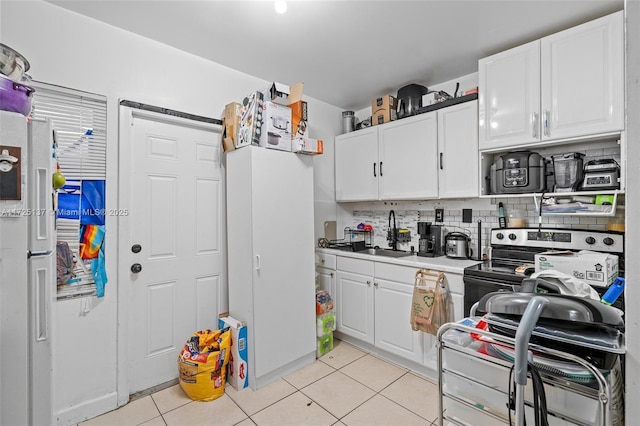 kitchen with sink, white cabinetry, light tile patterned floors, decorative backsplash, and electric range