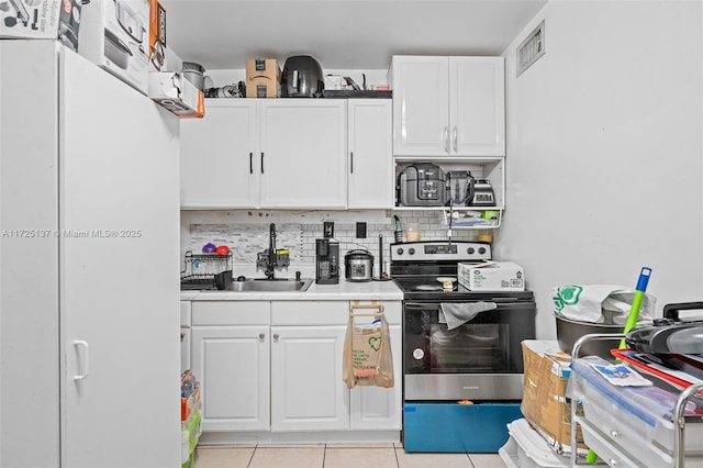 kitchen featuring electric stove, decorative backsplash, white cabinets, light tile patterned flooring, and sink