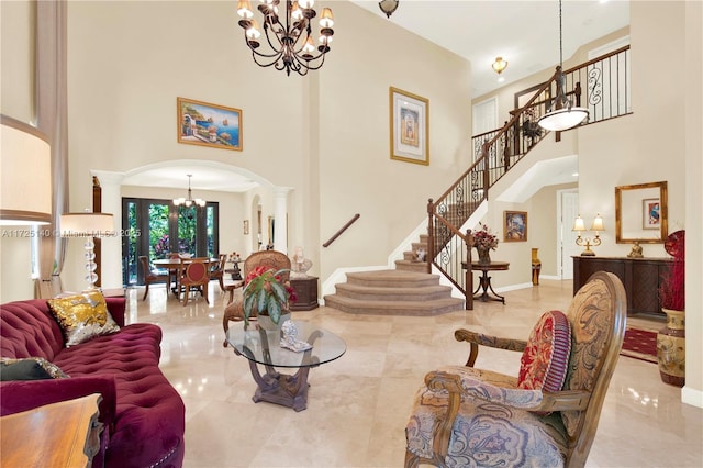 living room with decorative columns, a towering ceiling, and a notable chandelier