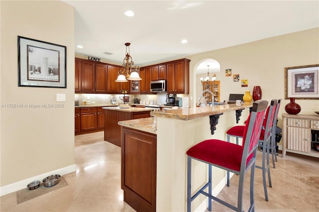 kitchen featuring a breakfast bar area, backsplash, a center island, decorative light fixtures, and a chandelier