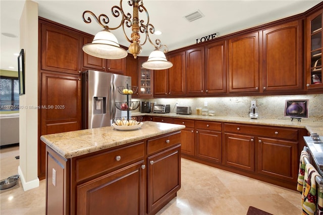 kitchen with tasteful backsplash, a center island, pendant lighting, and stainless steel fridge