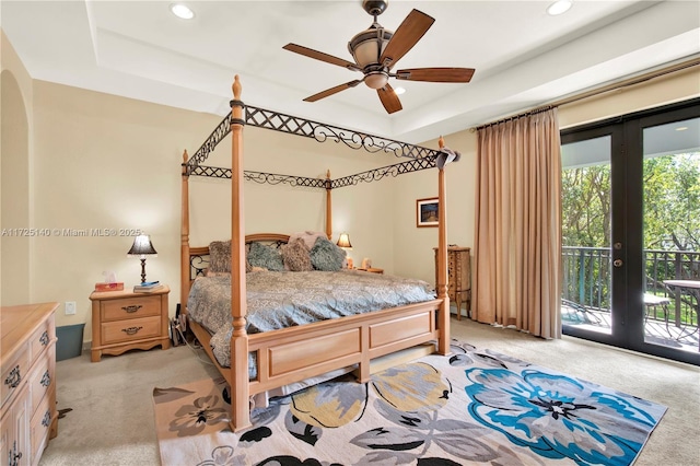 carpeted bedroom with access to exterior, a tray ceiling, french doors, and ceiling fan