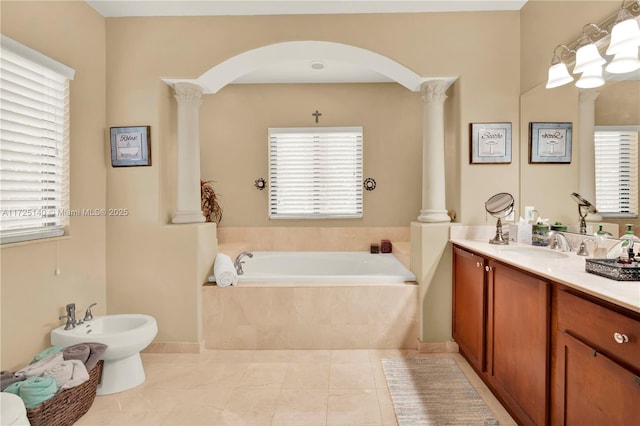 bathroom featuring tile patterned floors, ornate columns, a bidet, vanity, and tiled tub