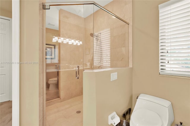 bathroom featuring a shower with door and toilet