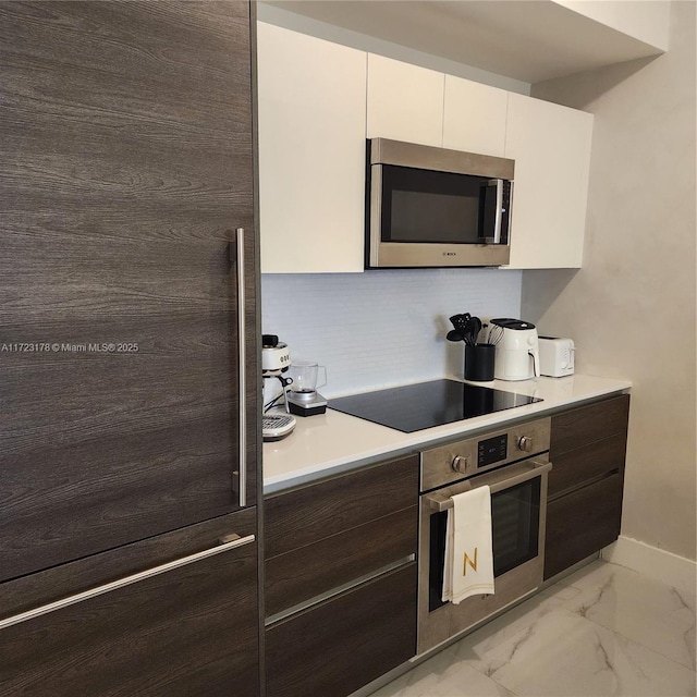 kitchen featuring white cabinets, appliances with stainless steel finishes, tasteful backsplash, and dark brown cabinetry