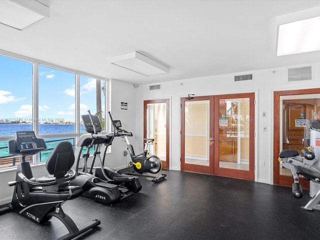 exercise room featuring a water view and french doors