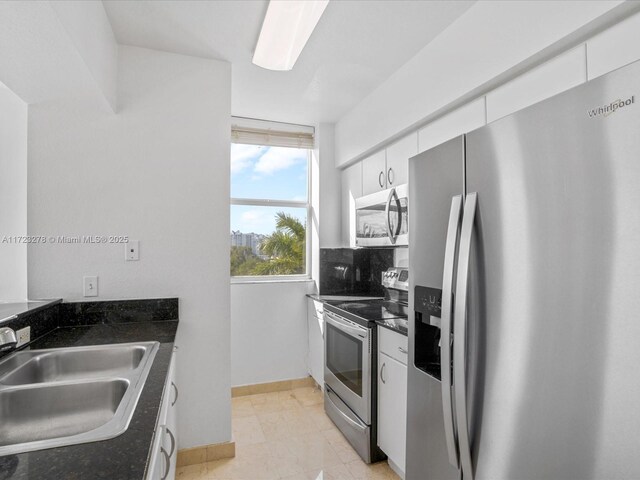 kitchen with light tile patterned floors, white cabinetry, stainless steel appliances, tasteful backsplash, and sink