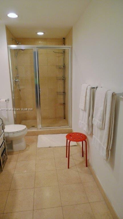 bathroom featuring tile patterned flooring, a shower with shower door, and toilet