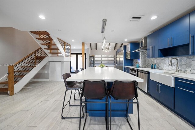 kitchen featuring blue cabinetry, appliances with stainless steel finishes, a center island, and decorative backsplash