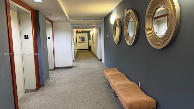 hall with baseboards, elevator, and light colored carpet