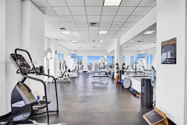 gym featuring a paneled ceiling, baseboards, and visible vents