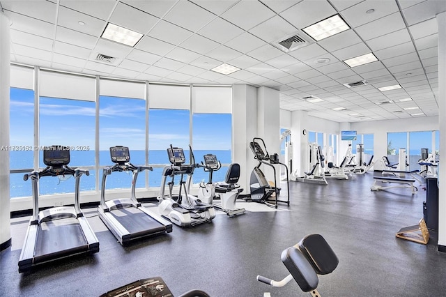 gym featuring a paneled ceiling, floor to ceiling windows, and visible vents