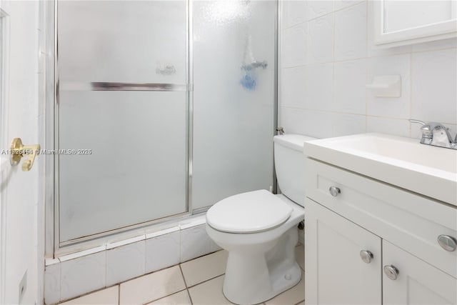 bathroom with tile walls, toilet, tile patterned floors, a shower with door, and vanity