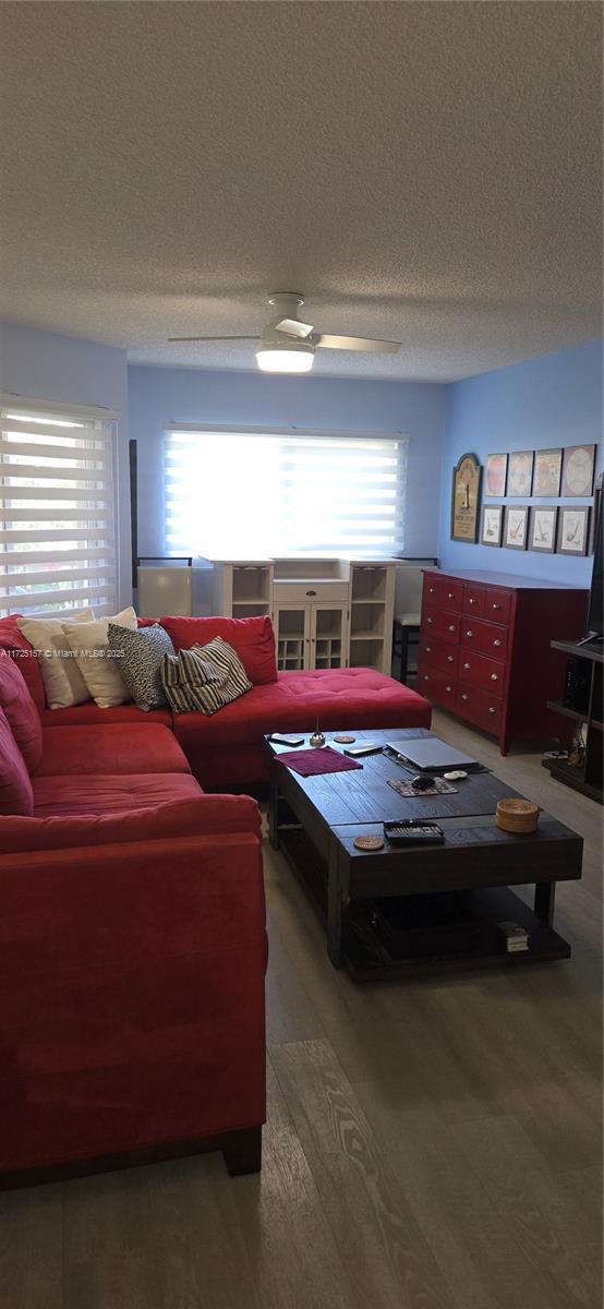 living room featuring hardwood / wood-style flooring, a textured ceiling, ceiling fan, and a healthy amount of sunlight