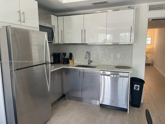 kitchen with stainless steel appliances, sink, white cabinets, tasteful backsplash, and gray cabinets