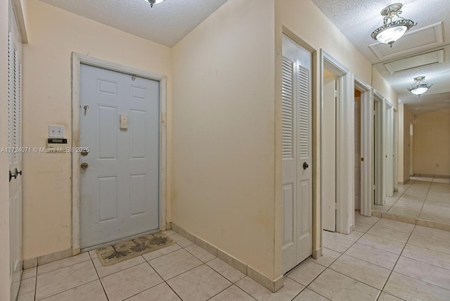 foyer entrance with a textured ceiling and light tile patterned flooring