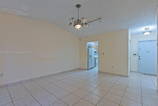 tiled empty room with lofted ceiling, an inviting chandelier, and a textured ceiling