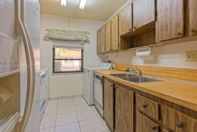 kitchen featuring white fridge, dishwasher, light tile patterned floors, sink, and washing machine and clothes dryer