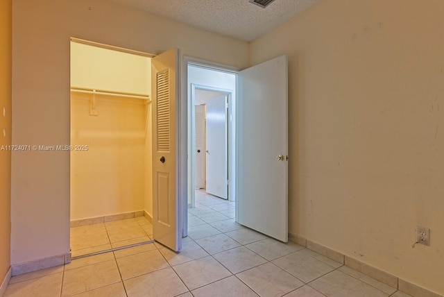 unfurnished bedroom with light tile patterned flooring, a closet, and a textured ceiling