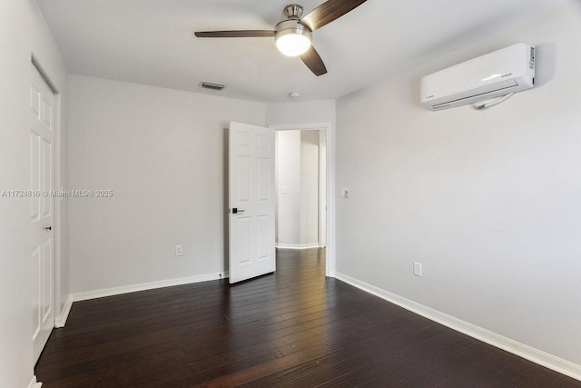 unfurnished room with dark wood-type flooring, a wall unit AC, and ceiling fan