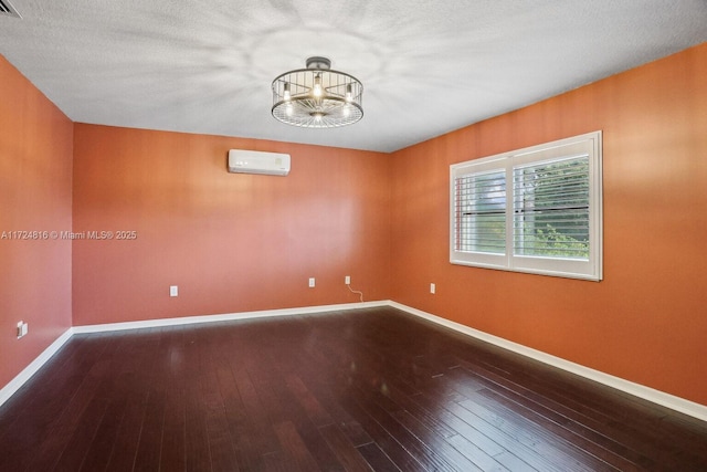 spare room with a notable chandelier, an AC wall unit, and hardwood / wood-style flooring