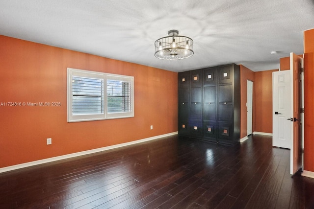 unfurnished bedroom featuring an inviting chandelier and dark hardwood / wood-style floors