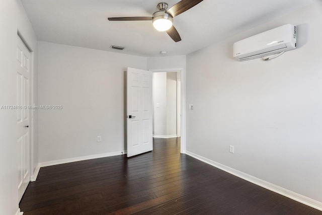 empty room featuring a wall mounted AC, ceiling fan, and dark hardwood / wood-style flooring