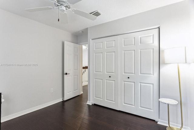 unfurnished bedroom with dark wood-type flooring, ceiling fan, and a closet