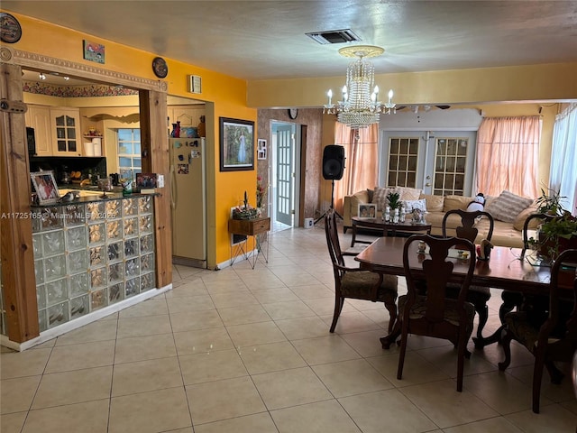 dining area with a chandelier, light tile patterned floors, and french doors