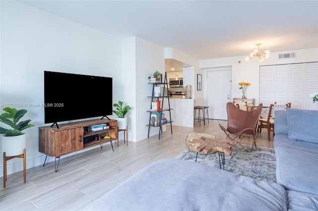 living area featuring a chandelier, visible vents, baseboards, and light wood-style flooring