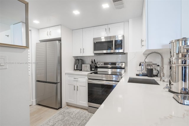 kitchen with light countertops, backsplash, white cabinets, visible vents, and appliances with stainless steel finishes