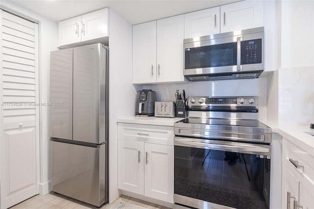 kitchen featuring stainless steel appliances, white cabinets, and decorative backsplash