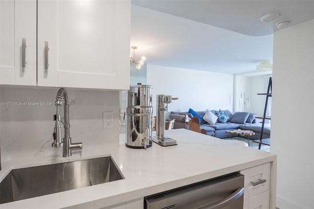 kitchen featuring light stone counters, sink, white cabinetry, stainless steel dishwasher, and tasteful backsplash