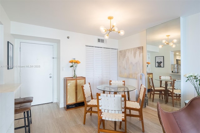 dining area featuring visible vents, light wood-type flooring, and an inviting chandelier