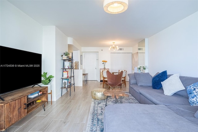 living area with light wood-style floors, an inviting chandelier, and visible vents