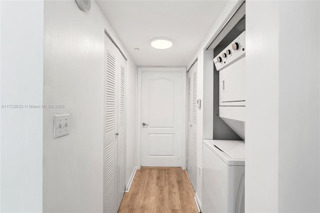 clothes washing area featuring stacked washer and clothes dryer and light hardwood / wood-style floors