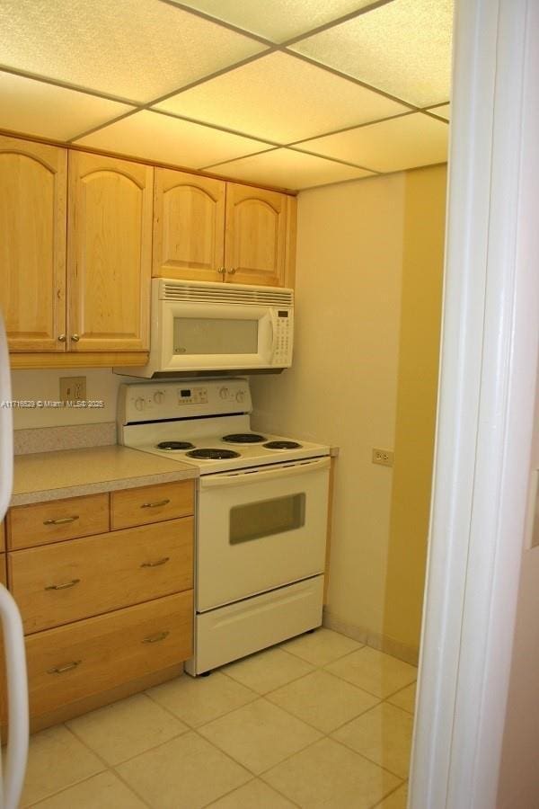 kitchen featuring white appliances, light brown cabinetry, and light tile patterned floors