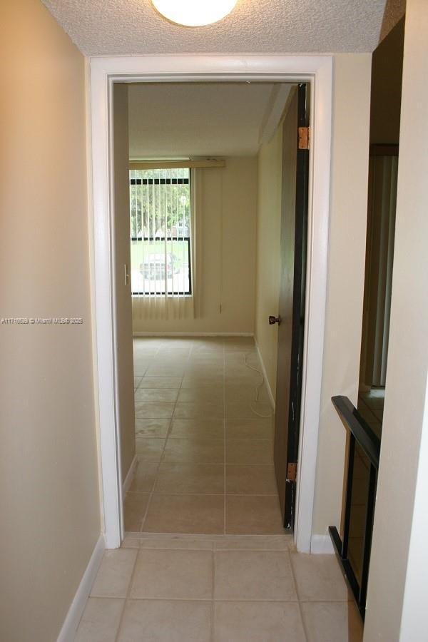 hallway featuring a textured ceiling and light tile patterned floors