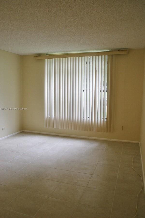 tiled empty room featuring a textured ceiling