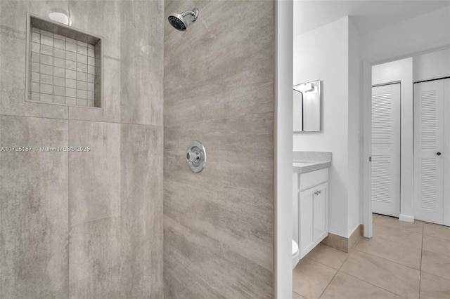 bathroom with a tile shower, vanity, and tile patterned floors